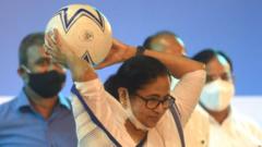পশ্চিমবঙ্গের মুখ্যমন্ত্রী মমতা ব্যানার্জী হাতে একটি ফুটবল নিয়ে ছুঁড়ছেন