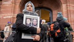 Syrian campaigner of the Caesar Families Association Yasmen Almashan holds pictures of victims of the Syrian regime as she and others wait outside the courthouse where former Syrian intelligence officer Anwar Raslan is on trial in Koblenz, western Germany on January 13, 2022
