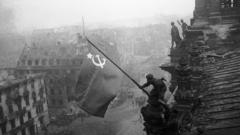 A Soviet soldier pictured hoisting a flag over the Reichstag in 1945
