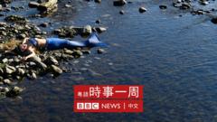 意大利都灵波河河岸一位身穿美人鱼服的抗议团体“反抗灭绝”成员躺卧石滩上参与气候变化抗议行动（17/2/2022）