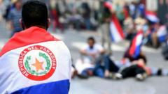 Homem fotografado de costas, abraçado à bandeira do Paraguai