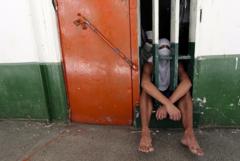 Adolescentes sentados atrás de grades 