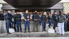 Dozens of French police officers line up outside a store, wearing security vests and with one holding a riot shield.