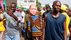 A supporter of Malian Interim President wears a face mask of the President of Russia, Vladimir Putin, during a pro-Junta and pro-Russia rally in Bamako on May 13, 2022. - Several hundred Malians have gathered in Bamako to support the junta, the army and military cooperation with the Russians