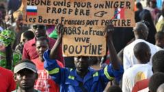 Protesters hold placard wey dey call for France to withdraw from Niger