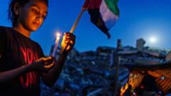 GAZA CITY, PALESTINIAN TERRITORY -- MAY 25, 2021: A young Palestinian girl lights a candle during a candlelighchildren t vigil to condemn the killing of and civilians, which is held over the rubble of homes destroyed by Israeli military strike during the 11-day escalation between Israel and Gaza military factions, which has now ended after an Egyptian-brokered ceasefire, bringing a momentary peace and calm to grieve and recover what was lost in Gaza City, Tuesday, May 25, 2021. In the same rubble, members of the Al-Madhoun family were killed ( Abdul Rahim Mohammed Madhoun (63) and his wife: Haijar Abu Sharkh al-Madhoun (60), and members of the al- al-Tanani family Ñ wife, husband and four children, were killed in an Israeli airstrike hit their houses in the dawn of the first day of Eid, on 13 May 2021, in addition to 7 family members of Al-Malfouh family were rescued from under the rubble of the same strike. 248 Palestinians were killed during this escalation, including 66 children. Eg
