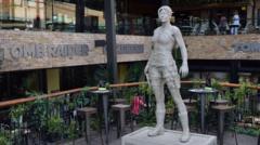 The nine foot (2.74m) statue of Lara Croft in a room with signs on the wall that says TOMB RAIDER