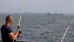 A fisherman watches the ship leave port