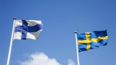 swedish and finnish flags waving on a sunny day