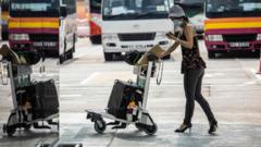 香港國際機場一號客運大樓外一位女士推著行李走向前往隔離酒店的旅遊大巴（23/9/2022）