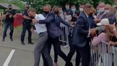President Macron being pulled away from the crowd.
