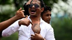 A pro-government supporter shows a tattoo on his chest of Prime Minister Mahinda Rajapaksa's portrait while protesting outside the prime ministers residence in Colombo on May 9, 2022. - Violence raged across Sri Lanka late into the night on May 9, 2022, with five people dead and some 180 injured as prime minister Mahinda Rajapaksa quit after weeks of protests.
