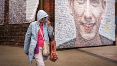 Woman walking in rain in front of street art.