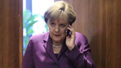 Umukuru w'Ubudage Angela Merkel akoresha telefone ye ngendanwa mbere y'inama y'umuryango w'Ubumwe bw'Uburayi i Buruseli mu Bubiligi, ku itariki ya 9/12/2011