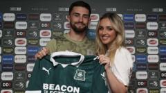 Owen and Jessica pose with a Plymouth Argyle shirt