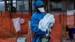 Trabalhador de saúde carrega um bebê de quatro dias, suspeito de ter Ebola, em um Centro de Tratamento de Ebola apoiado por MSF (Médicos Sem Fronteiras) em Butembo, República Democrática do Congo