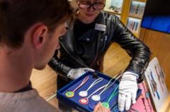 A female shop assistant at a Swatch store shows a blue box with eight Royal Pop pocket watches of different designs to a man.