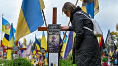 A woman looks at the photograph of a perished Ukrainian soldier on the graveside cross in the field of honorary burials at the Lychakiv Cemetery, Lviv, western Ukraine, on 28 October 2023