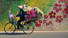 Person on a bike cycling past a colourful wall decorated with flowers