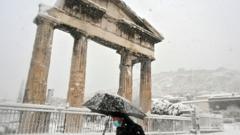 A man holding an umbrella in snow near the Roman Agora in central Athens