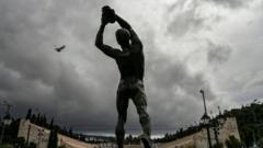 एथेन्सको प्यानाथेनियक रङ्गशालाको अगाडि रहेको एक मूर्ति। यही स्थानबाट आधुनिक ओलिम्पिक खेल शुरू भएको थियो