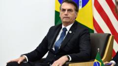 Bolsonaro sentado em cadeira com bandeiras do Brasil e de outro país atrás
