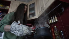Жінка варить каву на газовій плиті під час відключення світла у Києві, грудень, 2022 рік