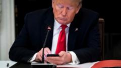 President Donald Trump uses his mobile phone
