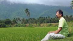 Sridhar sitting near a paddy field