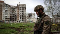 A Ukrainian serviceman walks near a residential building damaged by shelling in the frontline city of Bakhmut