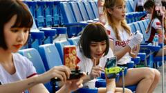 Rakuten Monkeys cheerleaders use their phones to interact online with their fans during the Chinese Professional Baseball League (CPBL) game between the Rakuten Monkeys and CTBC Brothers, at the Taoyuan Baseball Stadium on May 2, 2020, amid the COVID-19 coronavirus pandemic.