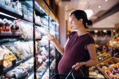 Mulher grávida olhando produto em supermercado