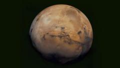 A photograph of Mars, a beige looking planet with dark black craters and ravines