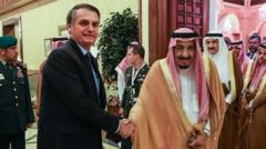 Bolsonaro e o rei apertando as mãos e sorrindo contidamente