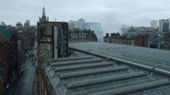 An aerial view from the south west as firefighters continue to damp down the remains of a fire in a building at the north east corner of Glasgow Central Station. The Victorian grid streets are seen around the glass roof of the railway station.