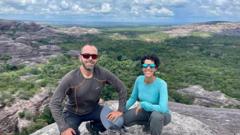 Dennis e Letícia em visita no Parque Nacional da Serra das Confusões, no Piauí. Eles estão agachados no topo de uma pedra alta e é possível ver a vegetação do parque abaixo deles.