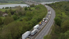 A drone image of the A13 looking toward Orwell Bridge. The carriageway closest to the camera is empty of vehicles. The other has long lines of vehicles queuing.