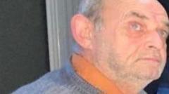 Robert Wilkin seen in a grey jumper and orange shirt
