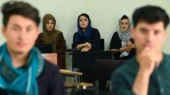 Tres estudiantes mujeres vistiendo abaya en el fondo del salón de clases, y dos estudiantes hombres delante.
