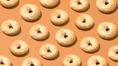 Cut out of bagels lined up in diagonal rows on a pale orange background.
