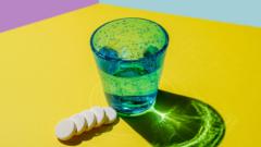 Effervescent tablets next to a glass of water. On a bright yellow background