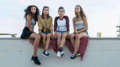 Quatro adolescentes sentadas no parapeito de um prédio