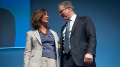 Eluned Morgan stood alongside Sir Keir Starmer at Welsh Labour conference last year. Morgan is wearing a blue top and grey suit, while Sir Keir is wearing a black suit, a blue tie, a white shirt and glasses.