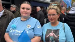 Vanessa Stansfield stands with her friend Emily outside the pub. He wears a blue t-shirt with a photo of Ricky Hatton in the boxing ring.