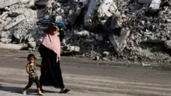 Palestinians walk by strikes
