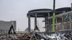 Remains of collapsed building in Bangkok with piles of cement and steel debris as dredgers operate to move obstacles