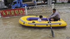 Residents make their way through a flooded street on an inflatable boat in disaster-hit Cangnan county of Wenzhou, east China's Zhejiang province, on 7 October 2013