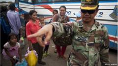 A Cambodian soldier helps workers after they cross the Thai border on June 17, 2014 in Poipet