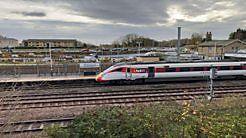 A passenger train at a platform, seen looking across the tracks.