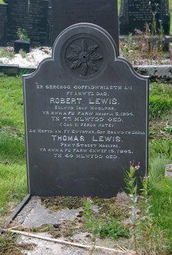 A colour photograph. The grave of Thomas  Lewis, in St Allgo Churchyard. The grey slate headstone is inscribed with silver lettering. He is buried with his brother Robert Lewis.